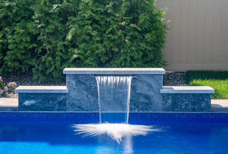 Wampler A - Hamilton, NJ - A water feature in the middle of a blue swimming pool surrounded by greenery