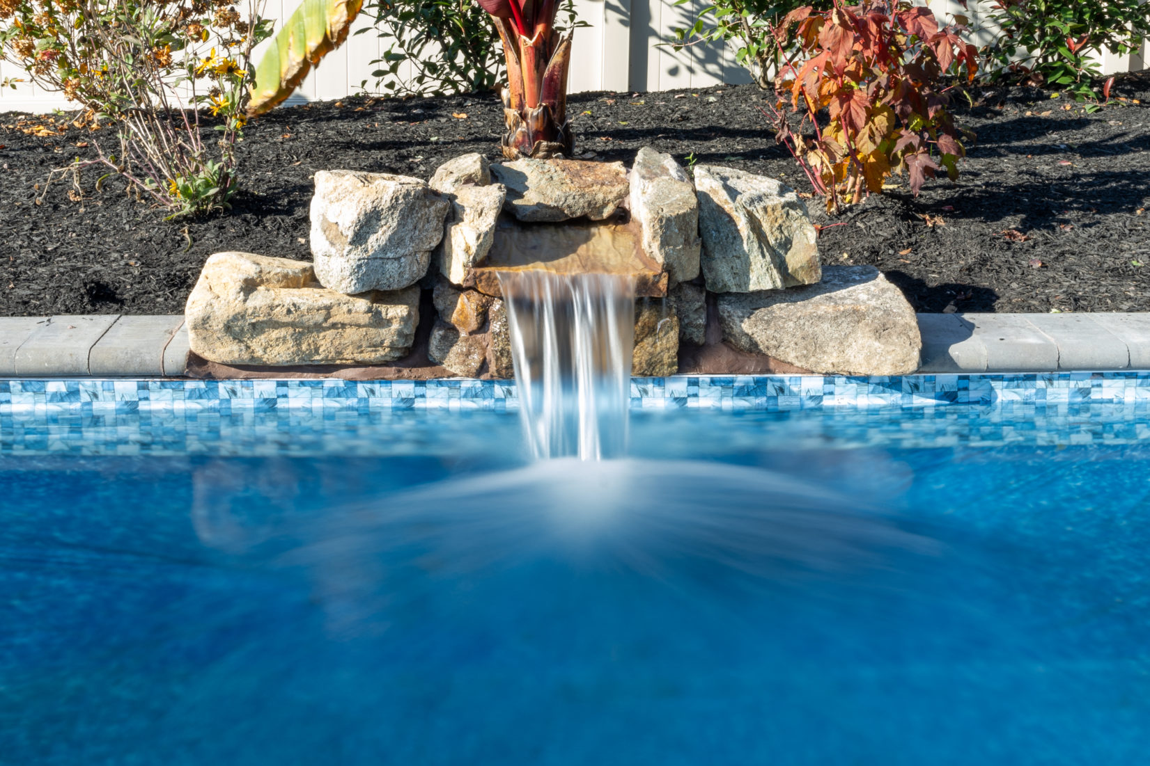Genesis M -  - A water feature in a swimming pool surrounded by plants and rocks