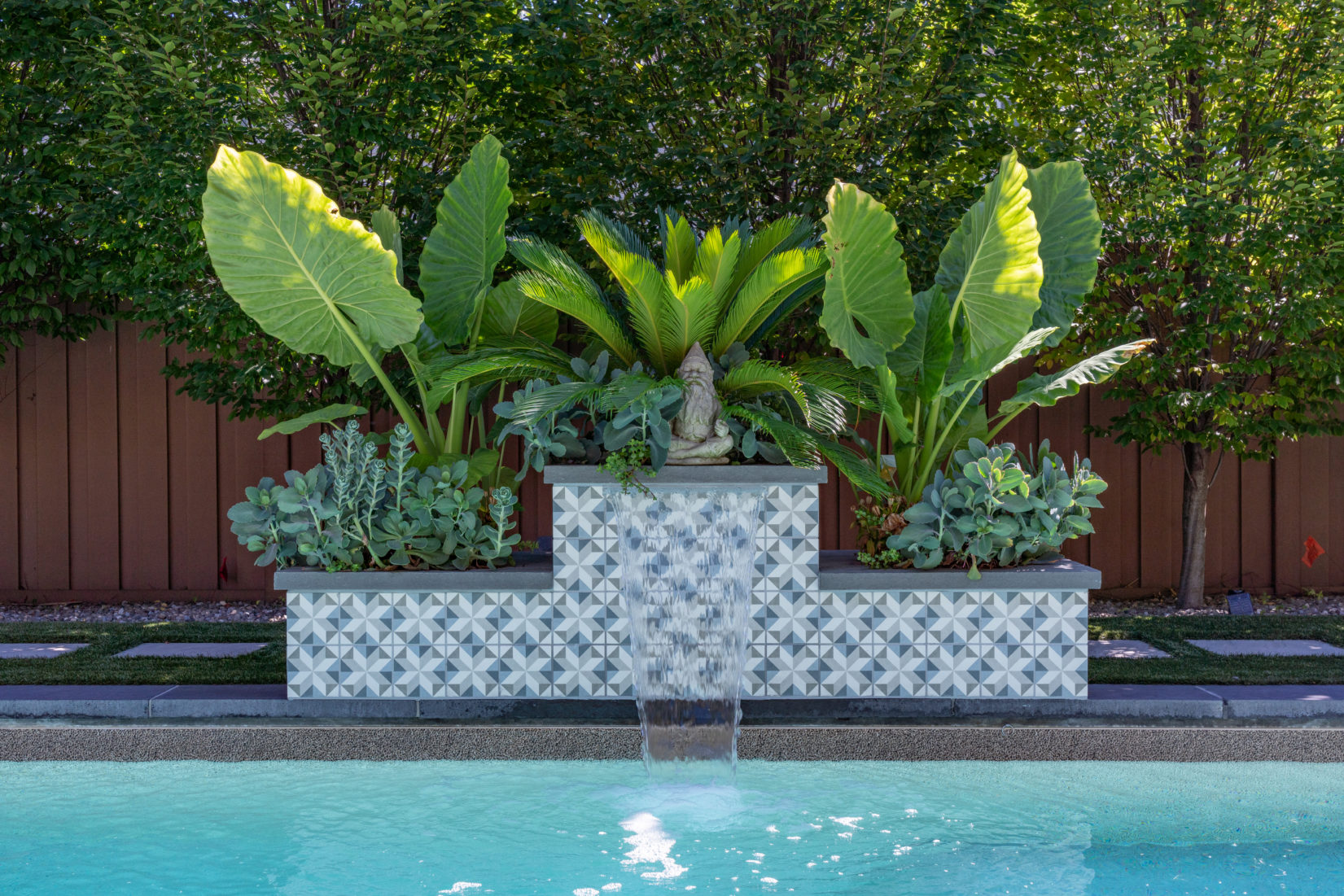 Rice A - Point Pleasant, NJ - A water feature in the middle of a swimming pool surrounded by lush greenery