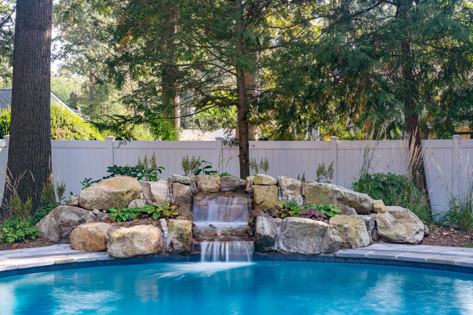 Urich A - Queenstown, MD - A swimming pool with a waterfall in the middle surrounded by lush greenery