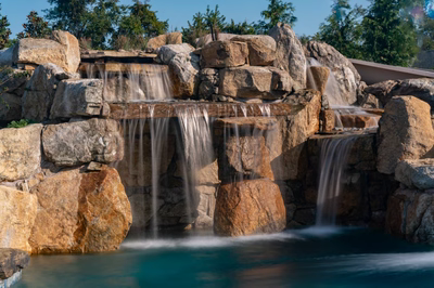 Tchupala G - Medford, NJ - A large rock waterfall in the middle of a pool surrounded by greenery