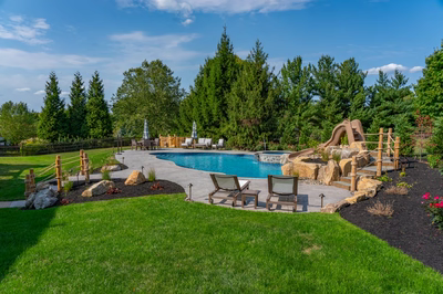 Abiqua F - Doylestown, PA - A backyard with a swimming pool and a water feature, surrounded by lush green grass and trees