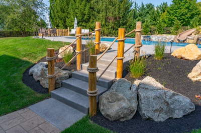 Abiqua H - Doylestown, PA - A backyard with a pool and a play area with rocks and a rope fence