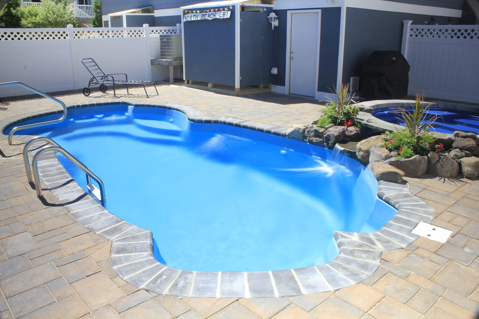 Single-tier natural stone boulder waterfall cascading into a blue freeform pool with lush plants