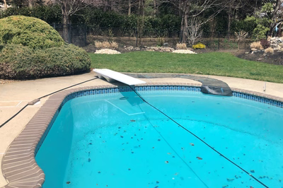Alamere A - Colts Neck, NJ - A blue swimming pool with a black fence and green grass in the background