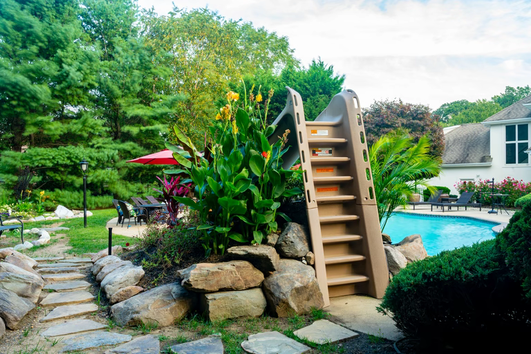 Natural stone boulder waterfall cascading into a pool surrounded by lush tropical plants