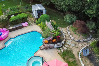 Alamere K - Colts Neck, NJ - A backyard with a swimming pool surrounded by lush greenery and colorful flowers