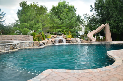 Alamosa F - Freehold, NJ - A swimming pool with a waterfall and a slide in a backyard setting