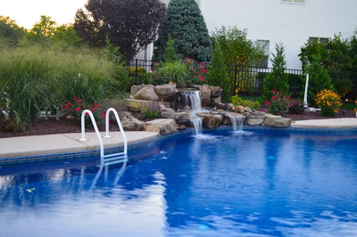 Alger C - Monroe, NJ - A swimming pool with a waterfall in the middle surrounded by flowers and greenery
