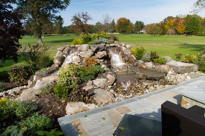 Alpine A - Moorestown, NJ - A rock garden with a waterfall in the middle of a lush green field