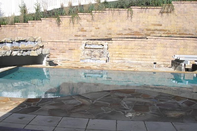 Angel A - Voorhees, NJ - A swimming pool with a stone retaining wall and a waterfall.