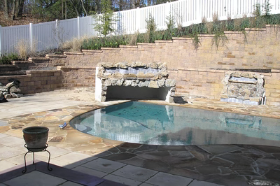 Angel C - Voorhees, NJ - A pool with a stone retaining wall and a waterfall feature.