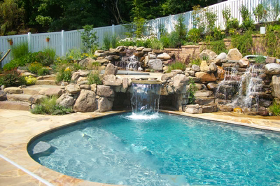 Angel D - Voorhees, NJ - A swimming pool with a waterfall feature in the middle of it surrounded by lush greenery and a white fence