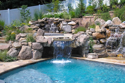 Angel L - Voorhees, NJ - A swimming pool with a waterfall in the middle surrounded by rocks and greenery