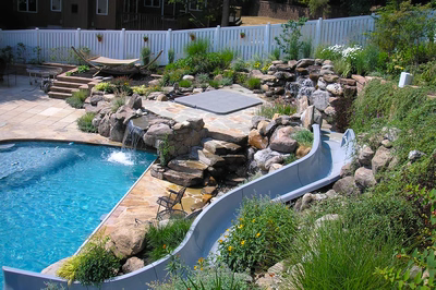 Angel N - Voorhees, NJ - A backyard with a swimming pool and a waterfall feature.