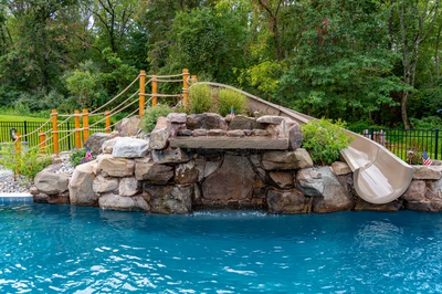 Antelope B - Ringoes, NJ - A swimming pool with a water feature and a slide in a backyard setting
