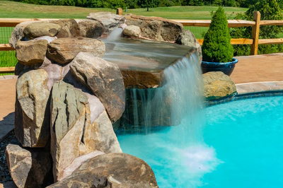 Apsley D - Gilbertsville, PA - A pool with a waterfall in the middle of it surrounded by rocks and greenery