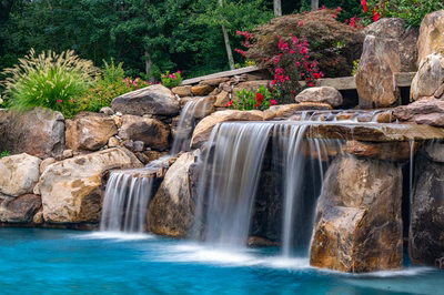 Aquatopia E - Williamstown, NJ - A beautiful waterfall in a natural setting surrounded by lush greenery and colorful flowers