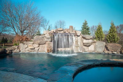 Armstrong B - Moorestown, NJ - A large stone waterfall in the middle of a pool surrounded by trees
