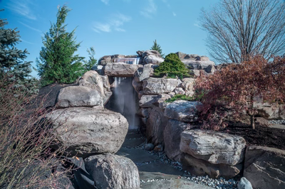 Armstrong F - Moorestown, NJ - A large rock structure with a waterfall in the middle surrounded by shrubs and trees
