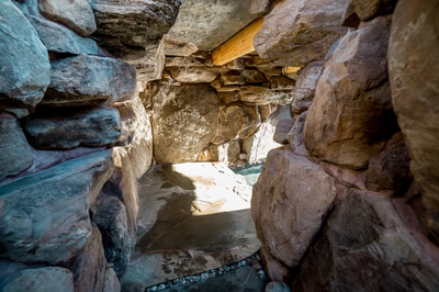 Armstrong K - Moorestown, NJ - A narrow passage through a rocky cave with pebbles on the ground