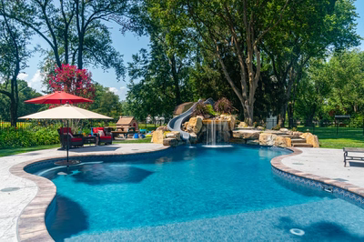 Augrabies J - West Deptford, NJ - A swimming pool with a waterfall and a water feature surrounded by lush greenery