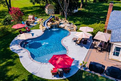 Augrabies M - West Deptford, NJ - A backyard with a swimming pool surrounded by lush green grass and patio furniture with umbrellas