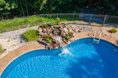 Azure F - Hillsborough, NJ - A swimming pool with a waterfall in the middle surrounded by greenery and flowers