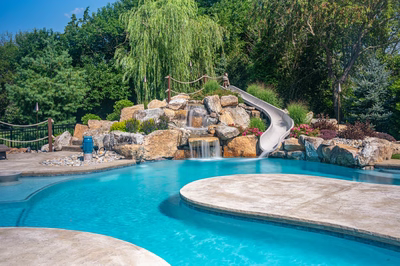 Bagley B - Williamstown, NJ - A swimming pool with a waterfall and a water slide surrounded by lush greenery