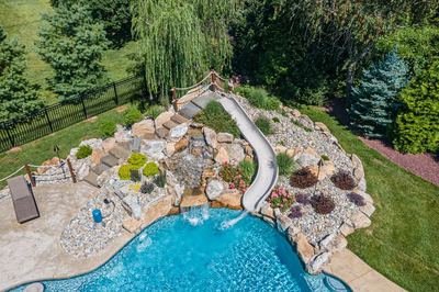 Bagley H - Williamstown, NJ - A backyard with a swimming pool and a water feature surrounded by lush greenery