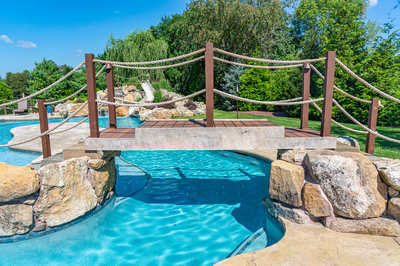 Bagley O - Williamstown, NJ - A wooden bridge over a swimming pool surrounded by rocks and rope structures