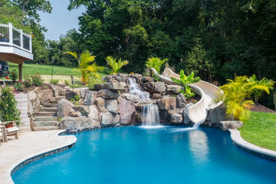 Barron A - Fallston, MD - A swimming pool with a waterfall and a slide surrounded by lush greenery