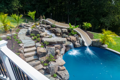 Barron C - Fallston, MD - A backyard with a water feature and a slide, surrounded by lush greenery