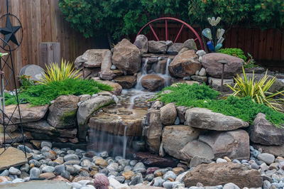 Basin G - Wenonah, NJ - A small waterfall surrounded by rocks and plants in a backyard setting