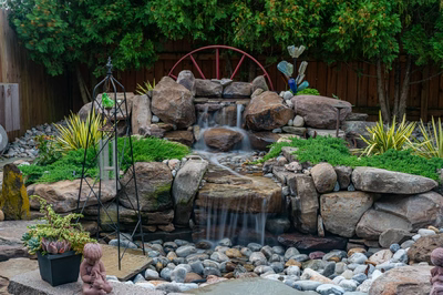 Basin H - Wenonah, NJ - A small waterfall surrounded by rocks and plants in a backyard setting