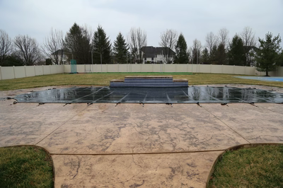 Beach A - Lumberton, NJ - A concrete pool deck with a tarp covering it, surrounded by a fence and a basketball court