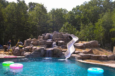 Beecher J - Wall, NJ - A swimming pool with a waterfall and a slide in a backyard setting