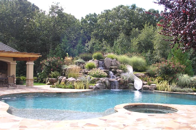 Beecher L - Wall, NJ - A swimming pool with a waterfall in the middle surrounded by lush greenery