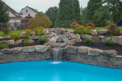 Beede B - Trappe, PA - A swimming pool with a waterfall in the middle surrounded by rocks and flowers