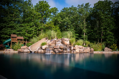 Belden B - Williamstown, NJ - A water feature with a slide in the middle of a swimming pool surrounded by trees