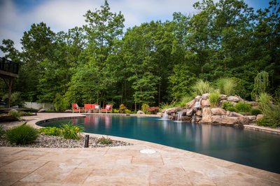 Belden F - Williamstown, NJ - A swimming pool surrounded by lush greenery and rocks with a waterfall.