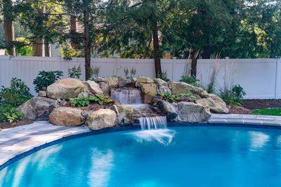 Belding C - Queenstown, MD - A swimming pool with a waterfall in the middle surrounded by lush greenery
