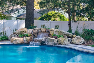 Belding F - Queenstown, MD - A swimming pool with a waterfall in the middle surrounded by rocks and greenery