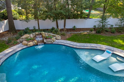 Belding I - Queenstown, MD - A swimming pool with a waterfall and lounge chairs in a backyard setting