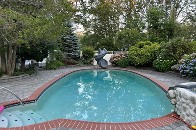 Benham B - Cape May Courthouse, NJ - A swimming pool surrounded by lush greenery and flowers, with a water feature in the middle