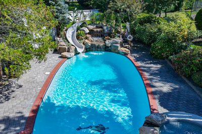 Benham C - Cape May Courthouse, NJ - A swimming pool with a waterfall and a water slide surrounded by lush greenery