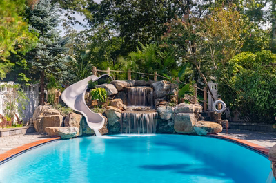 Benham D - Cape May Courthouse, NJ - A swimming pool with a water feature and a slide surrounded by lush greenery