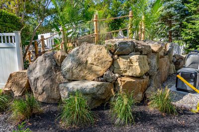 Benham G - Cape May Courthouse, NJ - A large rock wall with a rope fence in a backyard setting