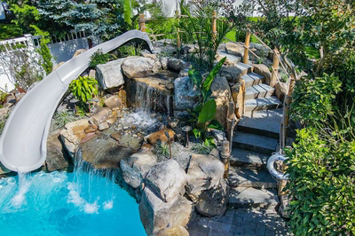 Benham I - Cape May Courthouse, NJ - A backyard with a water feature and a slide, surrounded by lush greenery