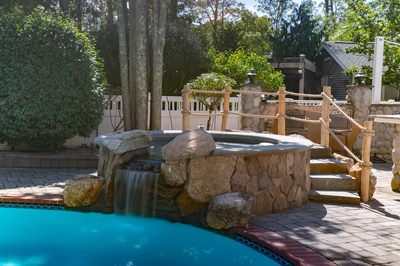 Benham R - Cape May Courthouse, NJ - A backyard with a pool and a waterfall feature surrounded by lush greenery